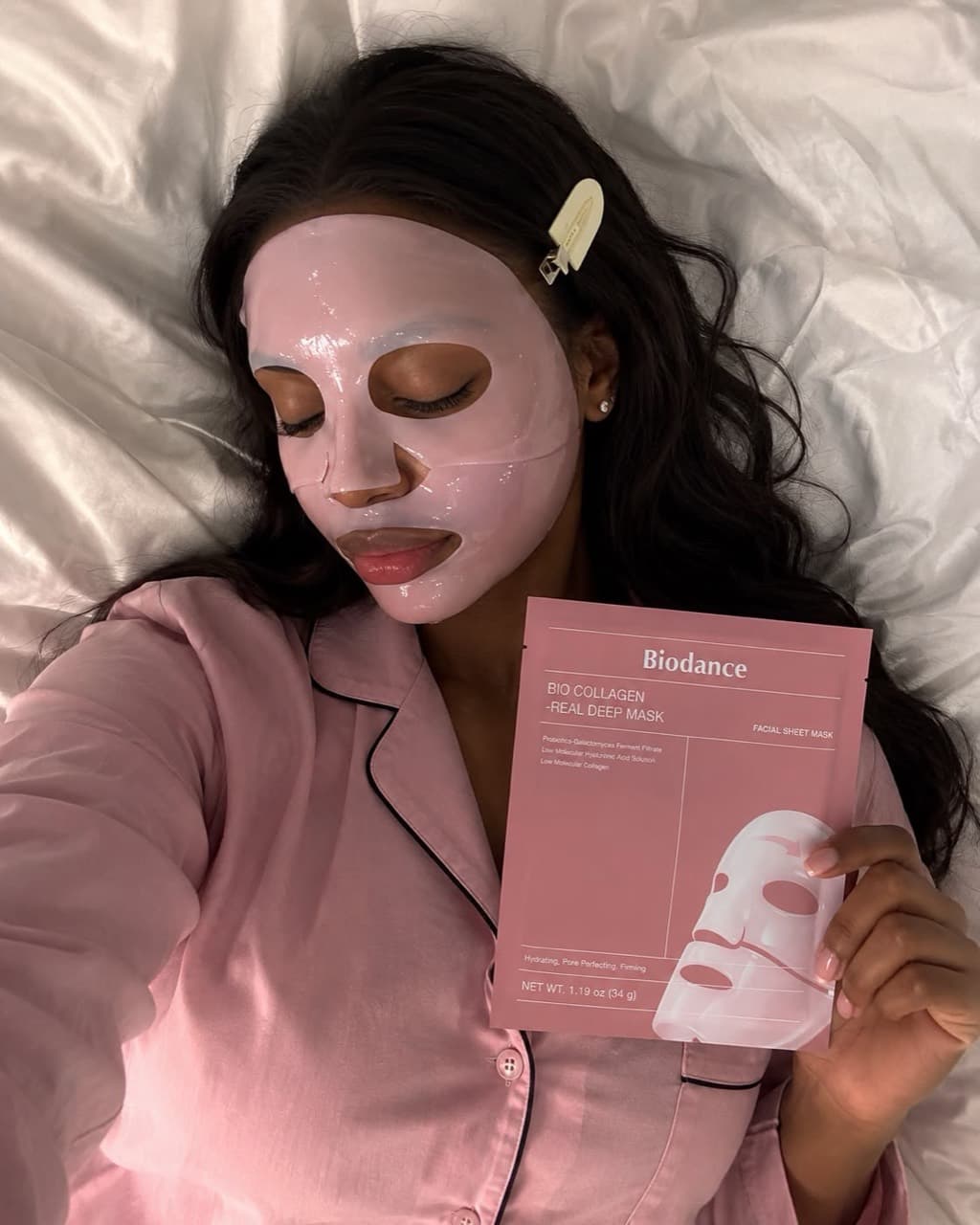 A woman relaxing with a pink sheet mask as part of her skincare routine